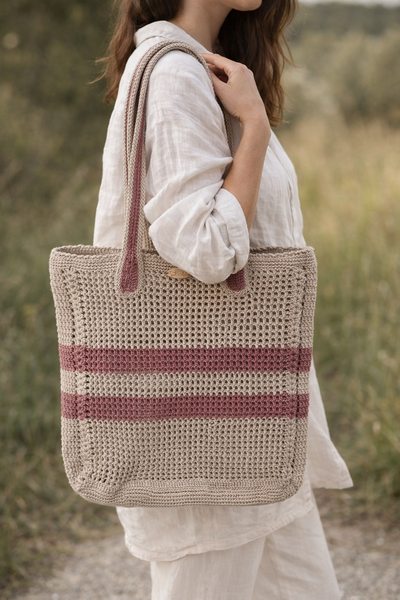 Handgefertigter Shopper „Zwei Streifen“ aus Häkelarbeit mit zwei Streifen, über der Schulter getragen im natürlichen Outdoor-Umfeld