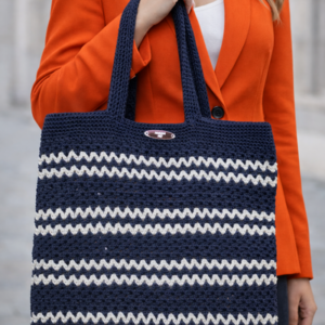 Frau trägt handgehäkelte Shopper Tasche in Marine und Weiß zu einem orangefarbenen Blazer